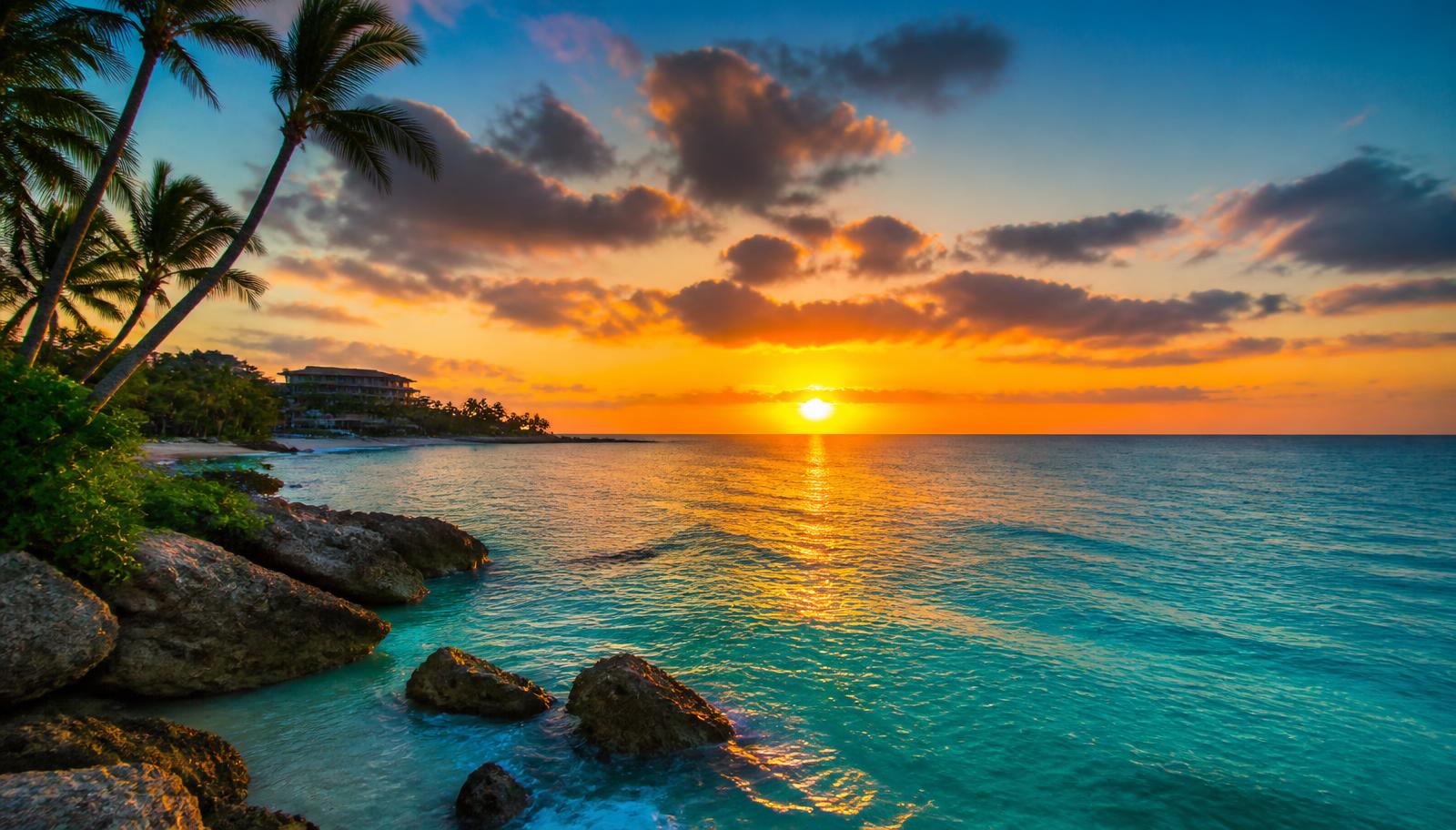 Pôr do sol panorâmico sobre o mar azul-turquesa do Caribe com coqueiros