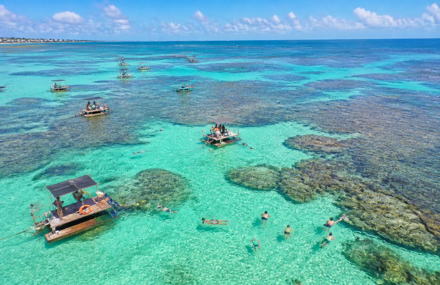 Piscinas naturais de águas transparentes com jangadas no mar de Maceió